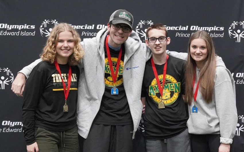 A four person Unified Bocce team, with their gold medals, stands in front of a backdrop 