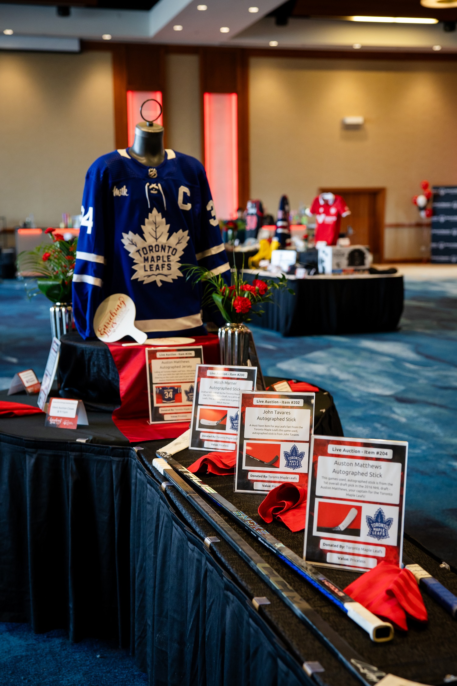 Items on display at a charity auction, including hockey sticks and a jersey