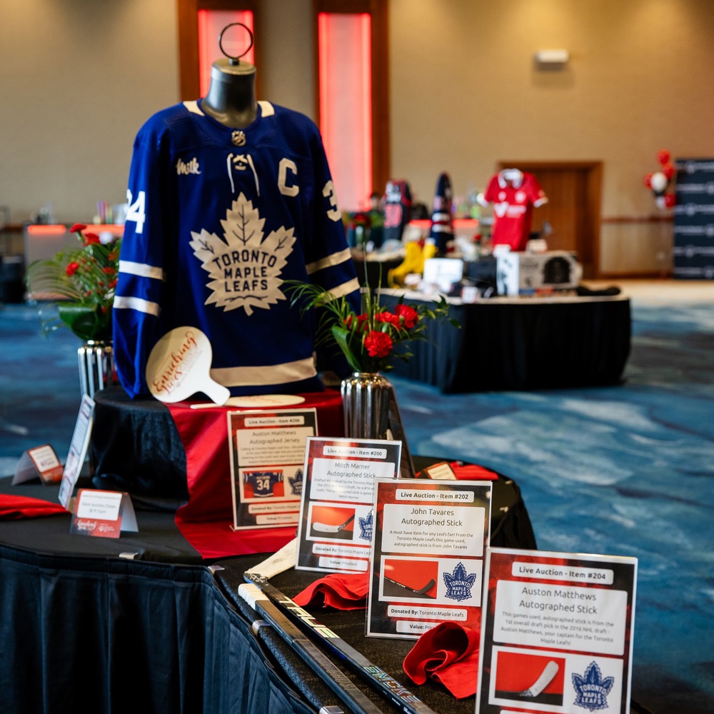 Items on display at a charity auction, including hockey sticks and a jersey