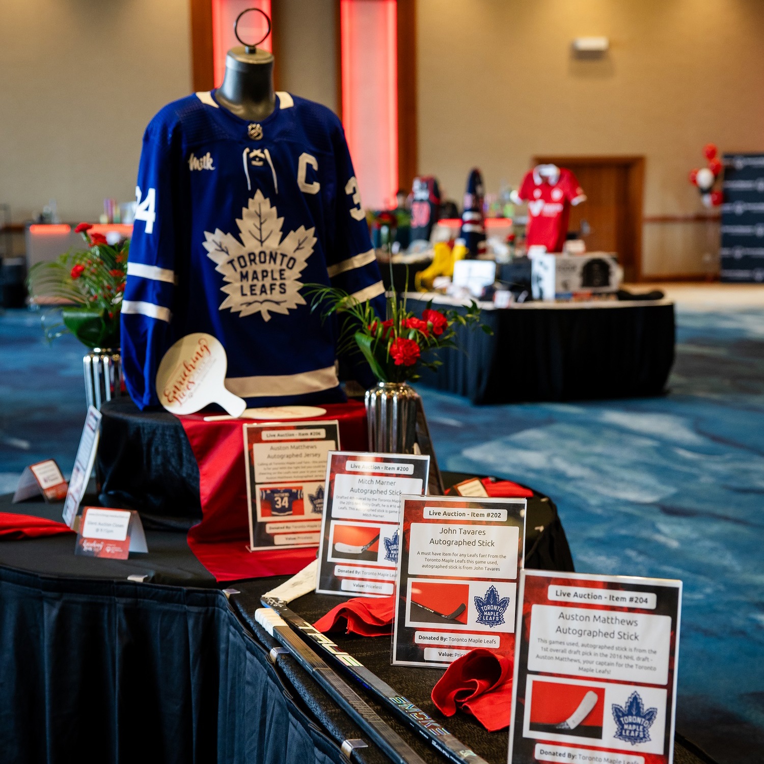 Items on display at a charity auction, including hockey sticks and a jersey