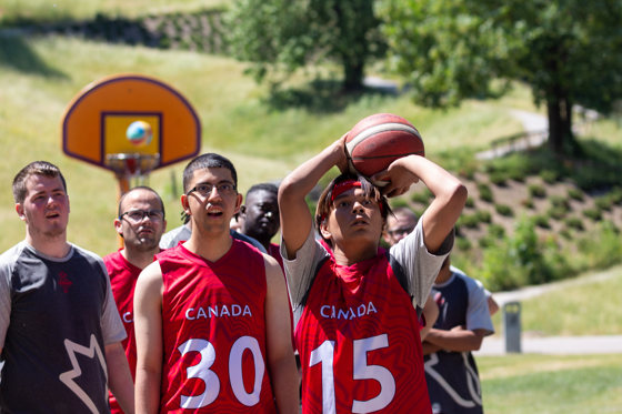 Diverse group of people on a basketball court. One boy is about to throw a basketball. 