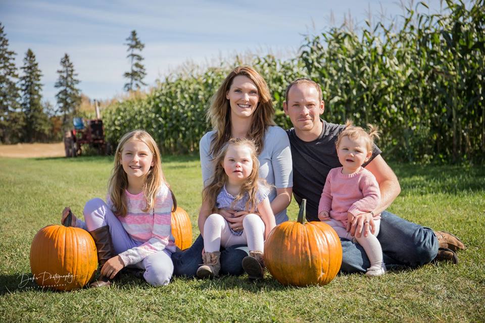 All five members of the Demeulenaere Family sit in a field for a photo.