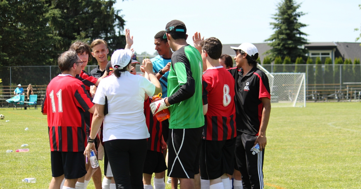 Roshan and his soccer team in a team huddle, cheering.