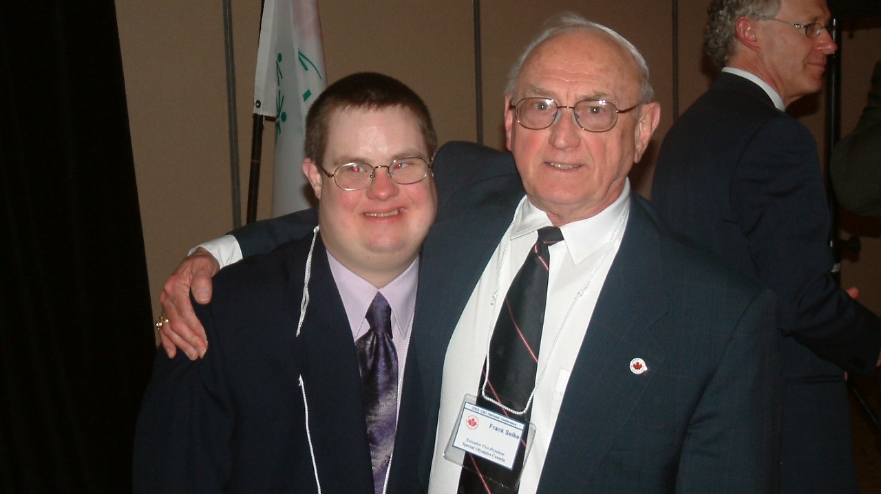 Frank Selke Jr. poses for a picture with his arm around a Special Olympics athlete