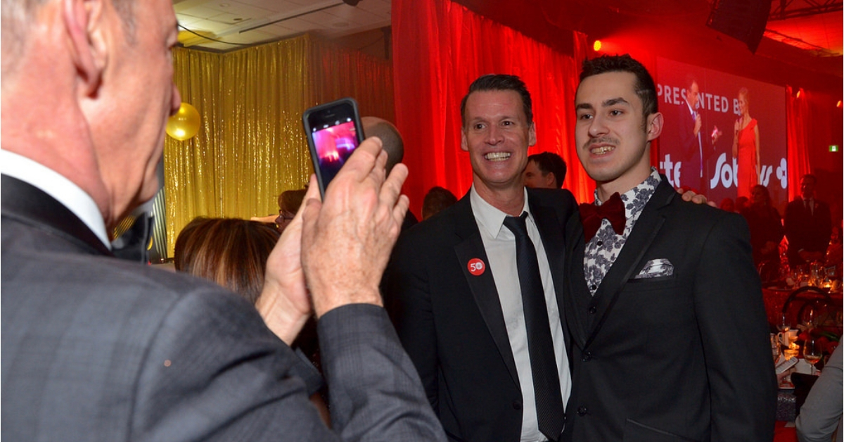 Mark Tewksbury speaks at a Special Olympics event with a microphone.