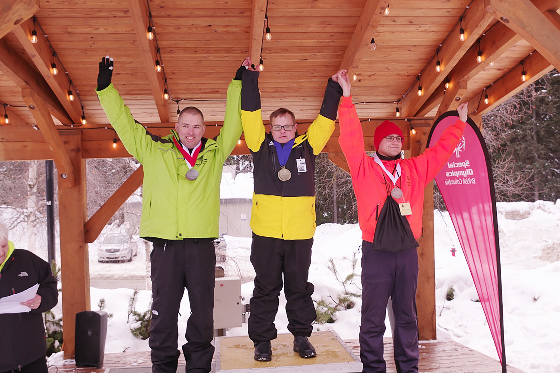 Three SOBC athletes on the podium with arms raised and medals around their necks