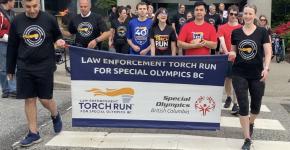 Torch Run participants running on the streets of Surrey holding LETR banner