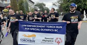 Torch Run participants running on the streets of Victoria holding LETR banner