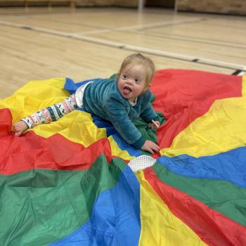 Toddler siting on colorful parachute