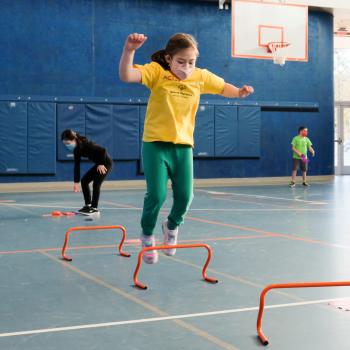 Athlete jumping over agility hurdles