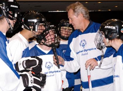 Darryl Sittler stands among Special Olympics athletes to interview them.