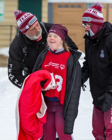 Coach talking to a snowshoeing athlete. Another athlete is standing to the right. 