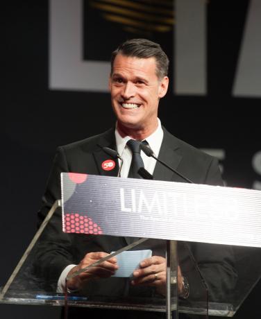 Mark Tewksbury speaks at a podium at Limitless 2018.