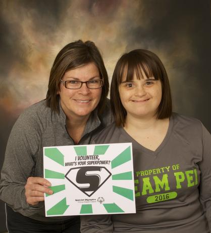 "Judy Gallant holds a sign that says "My super power is volunteering" next to Special Olympics PEI athlete Janet Charchuk."