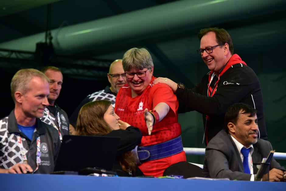 George Maclagan walks off the Powerlifting stage with athlete Christine Sullivan as she high fives judges.