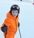 Wyatt poses for a photo on the ski hill in an orange snow suit.