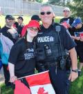 Mark Gugan, in his police uniform, poses for a photo with an athlete holding a Canadian flag.