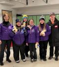 Debra Colvin standing and smiling with five of her athletes holding stuffed animal ducks and first place ribbons