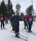 Mark Schnurr posing in his skis with four of his skiing athletes behind him
