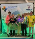 SOBC athletes smiling in neon costumes with SOBC Games banner in background