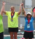 Kendall Salanski on top of podium raising hands with two other athletes