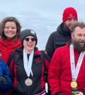 Jennifer smiling with medal around her neck with other people smiling beside her