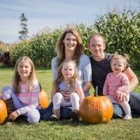 All five members of the Demeulenaere Family sit in a field for a photo.