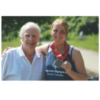 Dr. Frank Hayden stands with a Special Olympics athlete holding her medal.