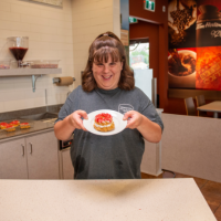"Special Olympics athlete Tori Ranson holds up a donut on a plate at TIm Hortons"