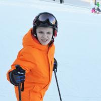 Wyatt poses for a photo on the ski hill in an orange snow suit.