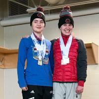 Madalyn, left, stands atop the podium smiling at the camera next to another athlete