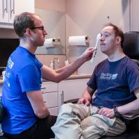 Eric sits in a chair getting his eyes checked.