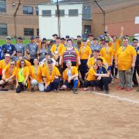A group of two softball teams pose for a team photo on a baseball diamond