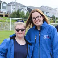 Volunteer Melissa Tobin smiles for a photo with an athlete on a soccer field.
