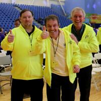 Three athletes and coaches smiling and giving a thumbs up