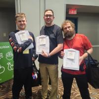 Three athletes smiling and holding up their clipboards