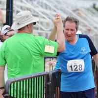 Special Olympics coach and athlete high five at a race finish line