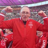 Wayne smiling and flexing both arms at the Opening Ceremony