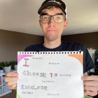 Josh holding a handwritten sign saying "I Choose to Include"