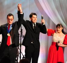 Matthew Williams on stage in formal dress with two fellow athletes