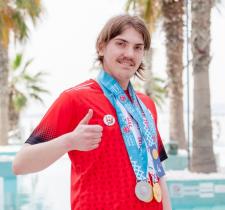 SO Team Canada swimmer Colby Kosteniuk gives the thumbs up while wearing his World Games medals.