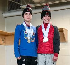 Madalyn, left, stands atop the podium smiling at the camera next to another athlete