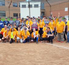 A group of two softball teams pose for a team photo on a baseball diamond