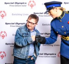 Kristi MacKay, dressed in her uniform, fist bumps an athlete at an event.