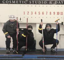 Curling athletes posing with their teammates and scoreboard