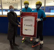 SOBC speed skaters holding a sponsor sign. 
