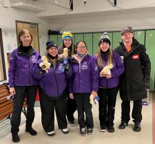 Debra Colvin standing and smiling with five of her athletes holding stuffed animal ducks and first place ribbons