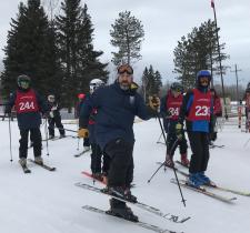 Mark Schnurr posing in his skis with four of his skiing athletes behind him