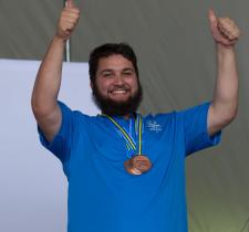 Daniel Thomas smiling with thumps up and medals around his neck