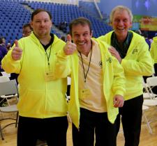 Three athletes and coaches smiling and giving a thumbs up